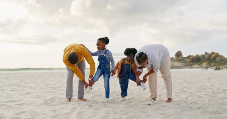 Foto de Verano, arena y una familia negra en la playa con zapatos para caminar o correr juntos. Feliz, viajar y los niños africanos con los padres preparándose para jugar junto al mar durante unas vacaciones. - Imagen libre de derechos