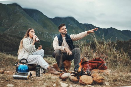 Photo for Couple, mountain and pointing in relax for camping, nature or outdoor scenery together by camp fire. Happy man and woman enjoying natural view, hiking or holiday vacation outside on trip or adventure. - Royalty Free Image