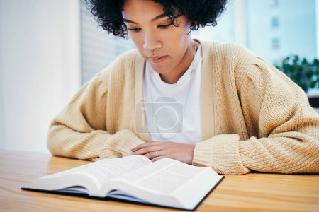Photo for Bible, reading and woman studying religion at desk in home, Christian faith and knowledge of God. Praise, learning and girl at table with holy book, gospel and inspiration for prayer in apartment - Royalty Free Image