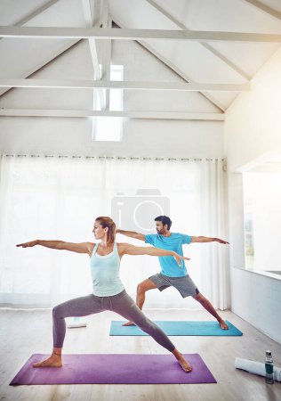 Téléchargez les photos : Couple, yoga et étirements en studio d'entraînement, d'exercice et d'entraînement holistique avec équilibre, pilates ou fitness. Des personnes ou un entraîneur personnel en posture guerrière pour le bien-être, la santé et l'apprentissage ensemble. - en image libre de droit