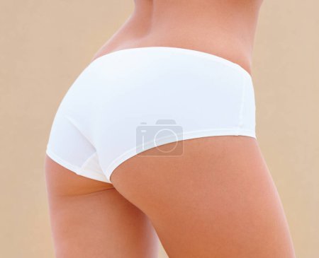 Foto de Butt, skincare and person in underwear for wellness, liposuction and diet on brown background. Beauty, natural and closeup of ass of woman with lingerie for cosmetics, dermatology and healthy body. - Imagen libre de derechos