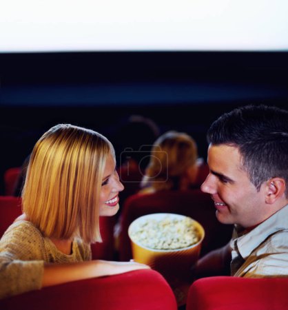 Téléchargez les photos : Cinéma, sourire et couple avec pop-corn, regarder un film ou manger à un rendez-vous romantique ensemble. Soirée cinéma, homme et femme heureux dans le théâtre avec des collations, l'amour et assis dans l'auditorium pour se détendre en public. - en image libre de droit
