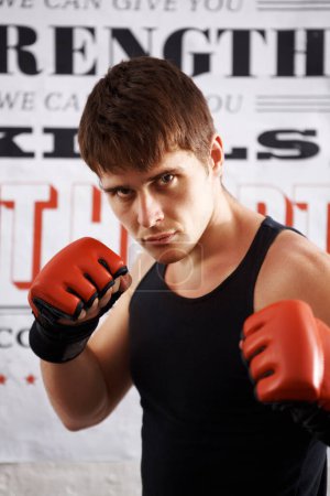 Photo for Man, portrait and professional fighter with boxing gloves in martial arts or MMA sports for self defense in dojo. Serious male person, athlete or boxer ready for fight, match or muay thai at the gym. - Royalty Free Image