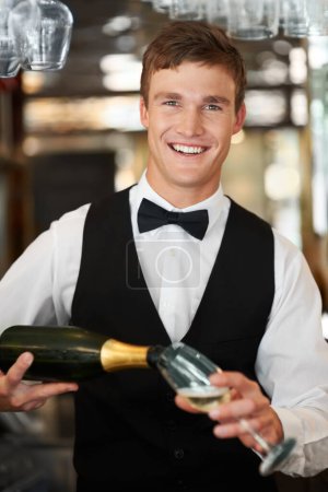 Photo for Man, bartender and waiter with champagne at restaurant for happy hour, hospitality industry or customer service. Portrait of barman, server or catering employee smile, wine glass and alcohol bottle. - Royalty Free Image