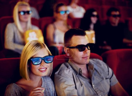 Photo for Cinema, 3d glasses and couple watching film, eating popcorn and romantic date together. Movie night, man and woman with smile in theater, snacks and eyewear, sitting in auditorium to relax at show - Royalty Free Image
