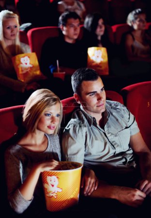 Photo for Cinema, love and couple with popcorn, watching film or eating on romantic date together. Movie night, man and woman in theater with snacks, romance and sitting in auditorium to relax at show premier - Royalty Free Image
