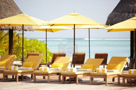 Téléchargez les photos : Maldives, chaises longues et parasol sur la plage pour le luxe, Voyage ou villa d'été pour des vacances ou des vacances. Tropical, loisir et océan pour station balnéaire, détente et île ensoleillée, extérieure ou caribéenne. - en image libre de droit
