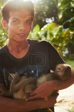 Foto de Zoológico, naturaleza y retrato del hombre con mono para el cuidado, conservación y rescate de la vida silvestre. Santuario, viaje y persona feliz con macaco en el medio ambiente, ecosistema y parque de animales para el turismo de Tailandia. - Imagen libre de derechos
