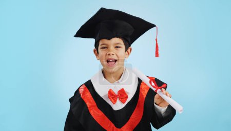 Téléchargez les photos : Diplômé, enfant et célébration avec portrait et bonheur en studio sur fond bleu pour l'éducation. Développement, enfant et succès avec expression enthousiaste, diplôme ou certificat de réussite. - en image libre de droit