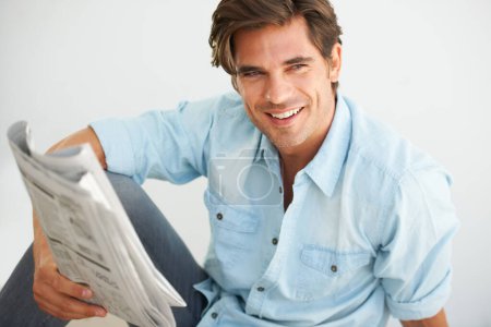 Foto de Periódico, joven y feliz leyendo información y relajándose en una mañana de fin de semana en casa. Sonríe, hombre inteligente y guapo que se enfría y disfruta de un diario diario en un apartamento moderno - Imagen libre de derechos