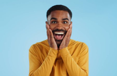 Photo for Hands on face, wow and excited black man in studio isolated on a blue background mockup space. Portrait, surprise and happy person in shock for good news, information and winner of bonus promotion. - Royalty Free Image