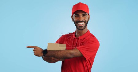 Photo for Advertising studio smile, delivery man and point at supply chain commercial, discount export info or distribution schedule. Courier service deal, mockup space and portrait person on blue background. - Royalty Free Image