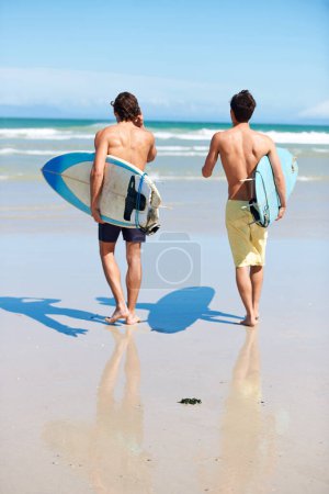 Téléchargez les photos : Courir, surfer et vue arrière d'amis hommes sur une plage avec liberté, énergie ou plaisir. Retour, fitness et surfeurs à l'océan excités pour les vacances d'été, séance d'entraînement ou passe-temps de sports nautiques à Hawaï. - en image libre de droit