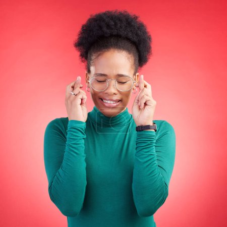 Photo for Fingers crossed, praying and black woman in studio with good luck sign for bonus, prize or giveaway on red background. Hope, wish and African lady with pray emoji for waiting, reward or lotto results. - Royalty Free Image