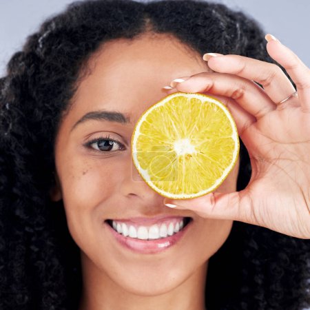 Photo for Portrait, wellness and woman with lemon eye for nutrition in closeup in grey studio background. Skincare, girl and vitamin c for facial treatment with natural organic food for dermatology or fruit - Royalty Free Image