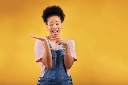 Foto de Branding, publicidad y una mujer negra señalando a su palma para la promoción de un producto en un fondo amarillo en el estudio. Sonrisa, marketing o espacio con una joven y feliz embajadora de la marca. - Imagen libre de derechos