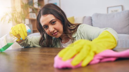Photo for Cleaning table, woman and spray for dust, furniture shine or bacteria on a surface of a house. Smile, working and a girl or cleaner spraying a desk in a living room for housekeeping or home service. - Royalty Free Image