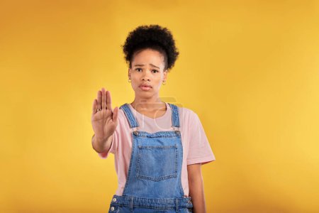 Photo for Stop, hand and warning with portrait of black woman in studio for emoji, no and voice. Rejection, opinion and sign with person on yellow background for protest, discrimination and forbidden icon. - Royalty Free Image
