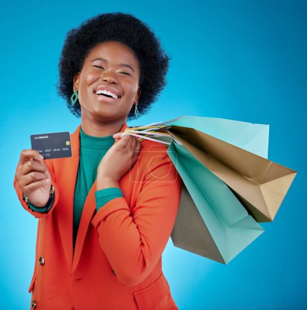 Photo for Woman, credit card and shopping bag for retail banking, finance and e commerce fintech or payment in portrait. Happy customer, fashion model or african person offer or debit on blue studio background. - Royalty Free Image