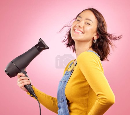 Photo for Hairdryer, wind and hair care with portrait of woman in studio for hairdresser, beauty and cosmetics. Shampoo, salon and hairstyle with face of asian person on pink background for product and smile. - Royalty Free Image