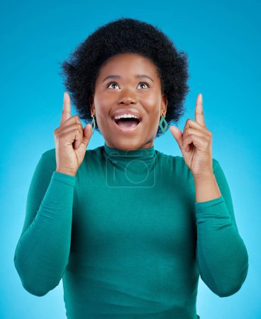 Photo for Hands, pointing up and black woman with wow news in studio for promo, announcement or deal on blue background. Omg, surprise and African female model show sale, coming soon or how to sign up steps. - Royalty Free Image