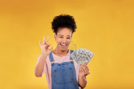 Photo for Okay, money and winner with portrait of black woman in studio for success, prize or achievement. Bonus, lottery and investment with person and cash on yellow background for dollar, profit or giveaway. - Royalty Free Image