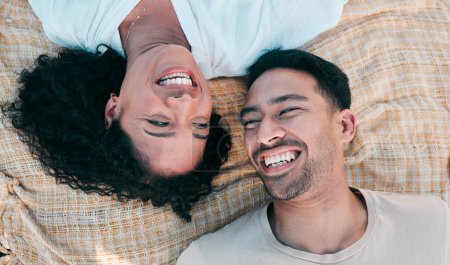 Photo for Face, picnic and smile with a couple laughing on a blanket from above, lying on the ground while on a date. Love, happy or funny with a man and woman bonding together for romance on valentines day. - Royalty Free Image