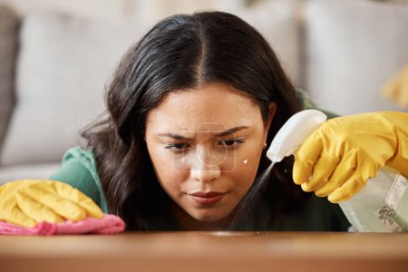 Photo for Face, spray bottle and a woman cleaning a wooden surface in her home for hygiene or disinfection. Gloves, product or bacteria and a cleaner with focus using detergent to spring clean in an apartment. - Royalty Free Image