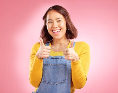 Photo for Smile, thumbs up and happy with portrait of woman in studio for support, agreement and motivation. Winner, emoji and success with person on pink background for achievement, thank you and vote sign. - Royalty Free Image