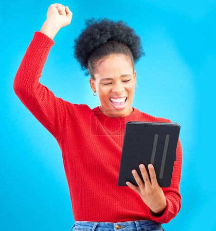 Photo for Happy woman, tablet and fist pump for winning, discount or sale against a blue studio background. Excited female person in celebration with technology for good news, bonus promotion or lottery prize. - Royalty Free Image