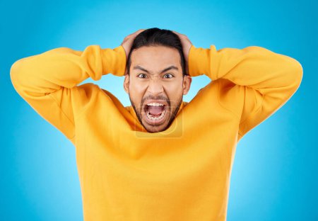 Photo for Angry, man and portrait with screaming in studio with burnout, anxiety and stress. Mental health, blue background and frustrated male person with yelling with anger about problem, mistake and issue. - Royalty Free Image