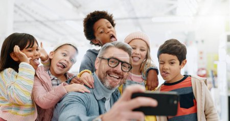 Photo for Selfie, children and teacher with funny face, smile and picture with educator, excited and happy. Kids, internet and cellphone for technology, online and memories for school, classroom or diversity. - Royalty Free Image