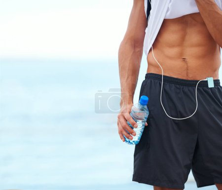 Photo for Man, fitness and abs with water bottle in outdoor, mockup and space by inspiration for wellness. Male athlete, pride and confident for bodybuilding by ocean, sea and progress by exercise and workout. - Royalty Free Image