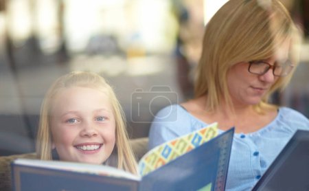 Téléchargez les photos : Lecture, portrait et mère avec enfant en librairie avec sourire, apprendre et se détendre dans la connaissance. Conte, maman heureuse et fille à la bibliothèque avec histoire, livres fantastiques et éducation dans la fenêtre. - en image libre de droit