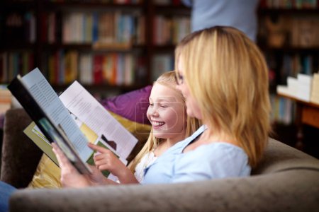 Téléchargez les photos : Lecture, livres et maman avec enfant à la bibliothèque avec sourire, apprendre et se détendre, étudier et la connaissance. Conte, mère heureuse et fille sur le canapé de la librairie avec histoire, fantaisie et éducation - en image libre de droit