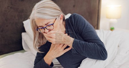 Illness, cough and senior woman in bed with allergies, flu or cold on a weekend morning at home. Sick, chest pain and elderly female person in retirement with asthma or infection in bedroom at house