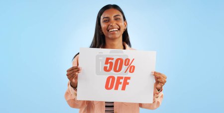 Photo for Woman, promotion poster and price portrait with sale, discount and billboard in studio. Excited, smile and happy from savings and deal paper with banner and promo with blue background and decrease. - Royalty Free Image