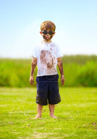 Photo for Child, boy or mud on face with goggles in garden, grass or field for playing, fun and summer weather. Kid, person or eyewear covered in dirt on lawn or backyard for muddy play, childhood or enjoyment. - Royalty Free Image
