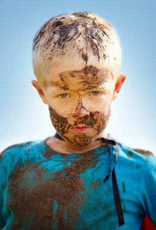 Photo for Boy, child and portrait with mud on face from playing, dirt or naughty in summer weather or water. Kid, person or grime with satisfaction for messy or dirty fun outdoor in sunshine or garden with sky. - Royalty Free Image
