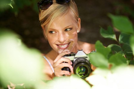 Photo for Smile, photographer and nature with woman in forest for trees, environment and relax. Shooting, camera lens and photography with face of female person in woods for travel, torusim and summer. - Royalty Free Image