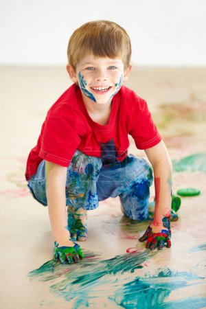 Photo for Portrait, smile and a boy painting on the floor of a studio for creative expression or education at school. Art, paint and an excited young child looking happy with his messy artistic creativity. - Royalty Free Image