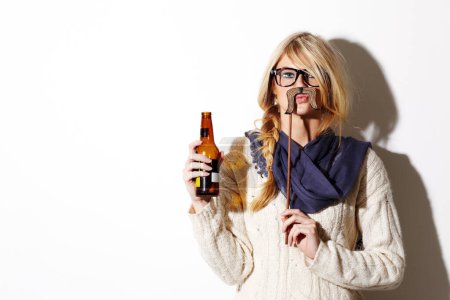 Photo for Portrait, mustache and a bottle of beer with a woman in studio isolated on a white background of space for mockup. Face, alcohol and costume with a young drunk person drinking at a party or event. - Royalty Free Image