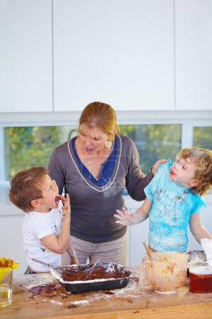 Photo for Family, baking and a mother yelling at her children for the mess in a home kitchen with naughty boys. Food, cake or ingredients with a woman scolding her kids while cooking in an untidy apartment. - Royalty Free Image