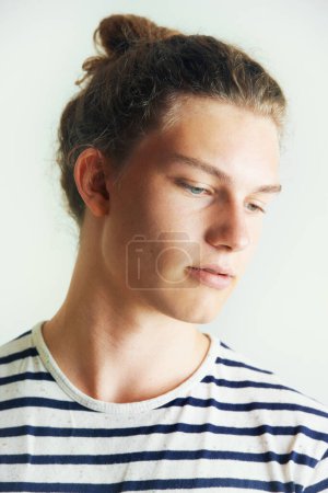 Photo for Young, man and thinking with face in studio for looking, idea or vision on white background in London. Male model, pose and hairstyle with bun, different and indie for clothes, fashion and trendy. - Royalty Free Image