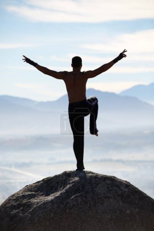 Foto de Karate, equilibrio y fitness hombre en la cima de la montaña para el entrenamiento corporal, el poder o el entrenamiento en el fondo del cielo azul. Artes marciales, maestría en MMA y taekwondo masculino en la naturaleza para el ejercicio, deporte o cardio matutino. - Imagen libre de derechos