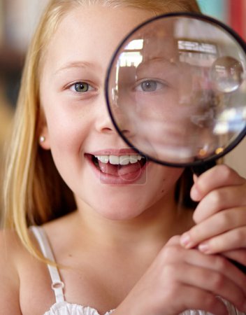 Photo for Happy, portrait and a child with a magnifying glass in a library for education, learning or inspection. Smile, young detective and a girl, kid or student with equipment for studying or attention. - Royalty Free Image