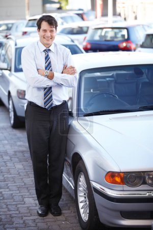 Photo for Portrait, lease and a man arms crossed at a dealership for car sale in a commercial parking lot. Business, rental and automobile trade with a happy young salesman outdoor for transport service. - Royalty Free Image