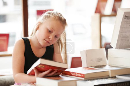 Photo for Girl kid, reading book and education, story for knowledge or entertainment with customer in bookshop. Library, store and learning for development and growth, fiction or literature with young child. - Royalty Free Image
