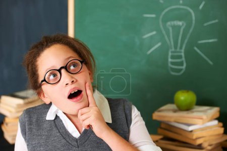 Photo for Child, thinking and light bulb on chalkboard for education, learning and knowledge with wow, ideas or solution in classroom. Girl, student or school kid with vision, inspiration and lightbulb doodle. - Royalty Free Image