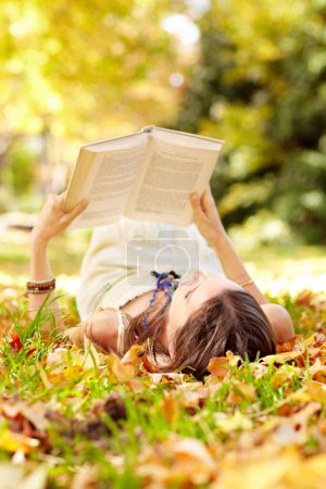 Photo for Reading, book and woman relax in park with novel in nature learning for education as student outdoor on campus. University, college and young person with textbook on grass field for scholarship. - Royalty Free Image